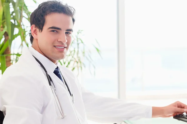 Side view of doctor sitting behind his desk — Stock Photo, Image