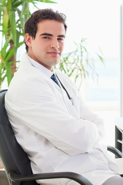 Vista lateral do médico sentado com os braços dobrados — Fotografia de Stock