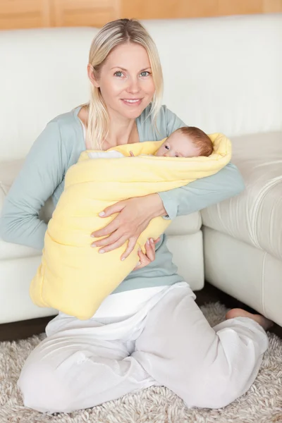 Mãe segurando seu bebê que está embrulhado em uma capa — Fotografia de Stock