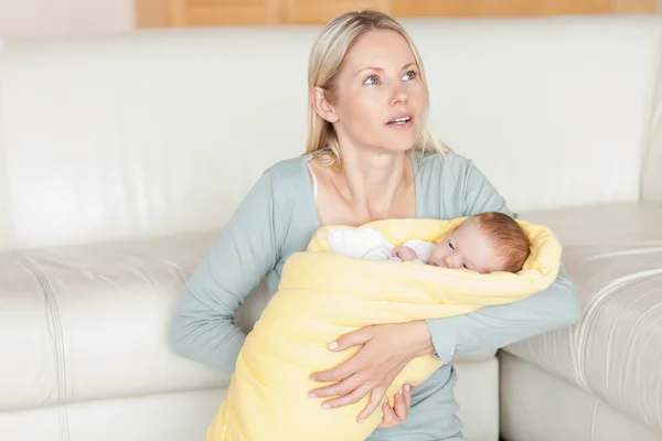 Mãe sentada com seu bebê na frente do sofá — Fotografia de Stock