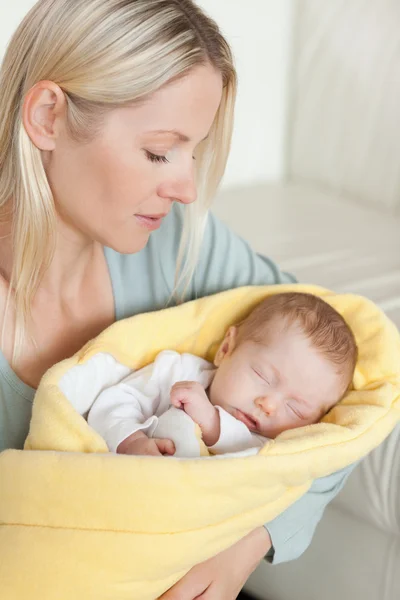 Mãe segurando seu bebê dormindo que está embrulhado em uma capa — Fotografia de Stock