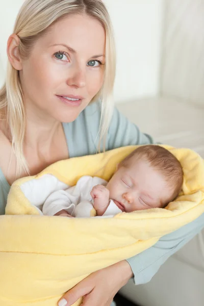 Mãe segurando seu bebê dormindo que está enrolado em uma capa — Fotografia de Stock
