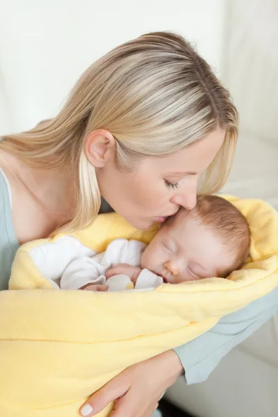 Любящая мать целует лоб своего ребенка — стоковое фото