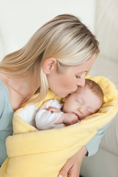 Любящая мать целует лоб своего новорожденного — стоковое фото