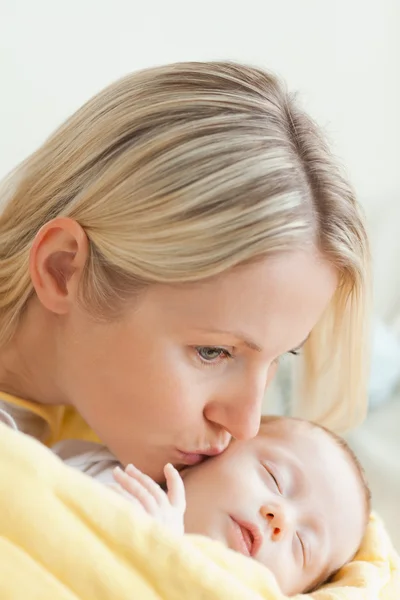 Madre cariñosa besando la mejilla de su bebé dormido — Foto de Stock