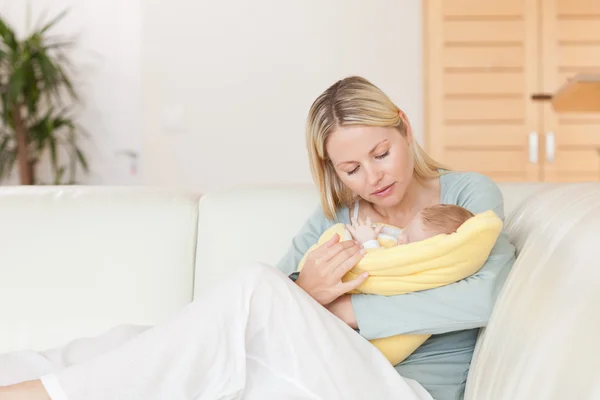 Mãe sentada no sofá com o bebê nos braços — Fotografia de Stock