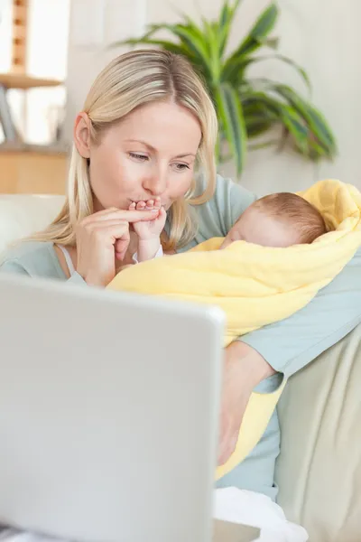 Madre cariñosa sosteniendo a su bebé en el sofá —  Fotos de Stock