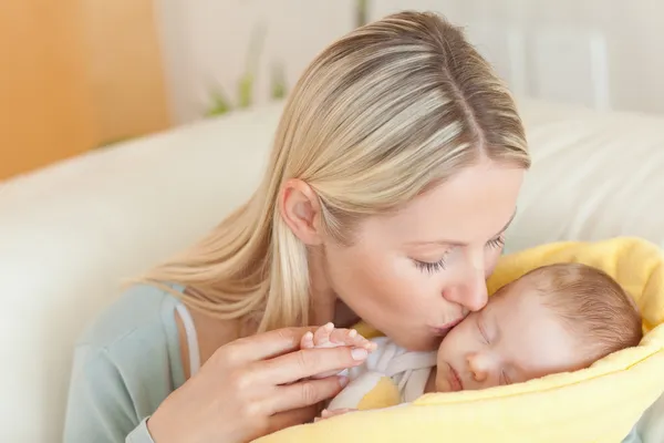 Мати на дивані цілує дитину — стокове фото