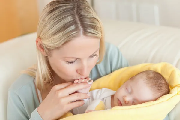 Mutter auf dem Sofa küsst ihrem Baby die Hand — Stockfoto