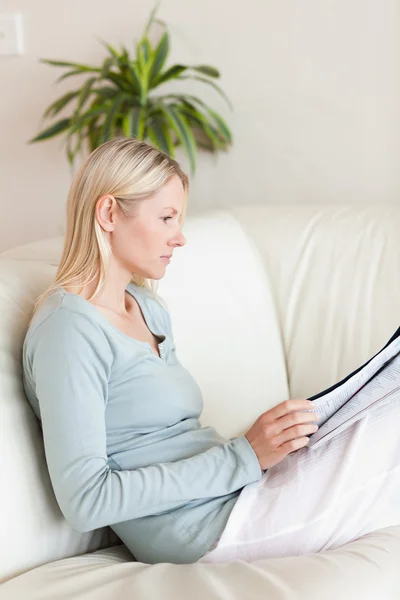 Widok z boku kobiety, czytanie na jej kanapie — Zdjęcie stockowe