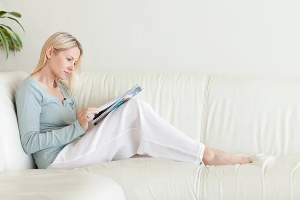 Vista lateral de la mujer mirando el catálogo en el sofá —  Fotos de Stock