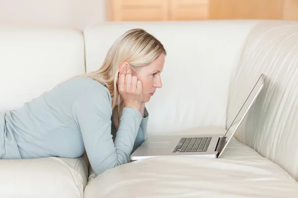 Side view of woman with laptop lying on the sofa — Stock Photo, Image