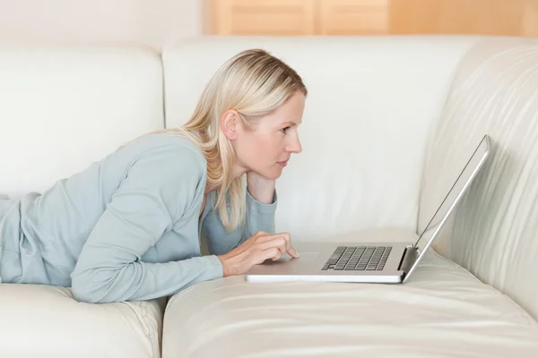 Side view of woman with notebook lying on the sofa — Stock Photo, Image