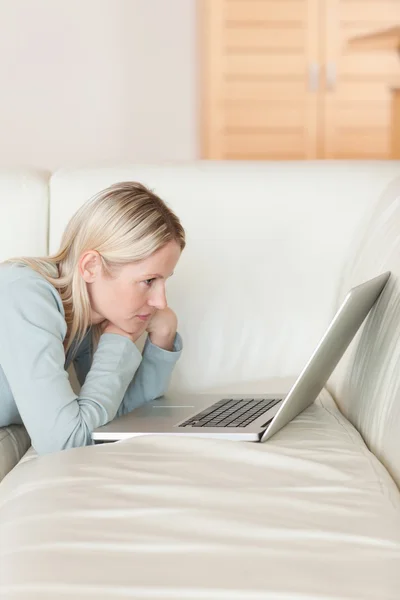 Side view of woman with notebook lying on the couch — Stock Photo, Image