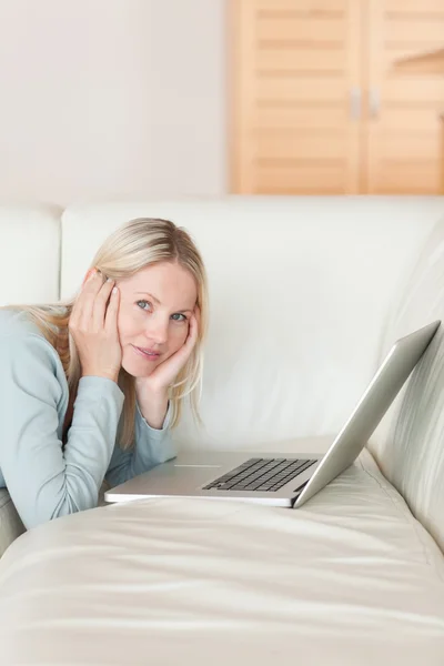 Vista laterale della donna sdraiata sul divano navigando sul web — Foto Stock