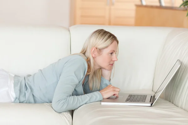 Side view of woman lying on the sofa surfing the web — Stock Photo, Image