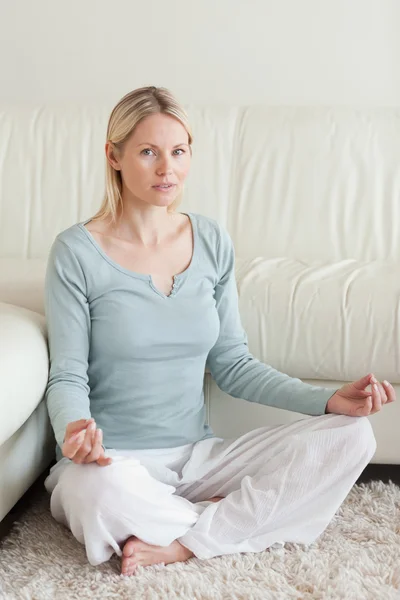 Kobieta krzyż legged siedzi na dywanie robienie yoga — Zdjęcie stockowe