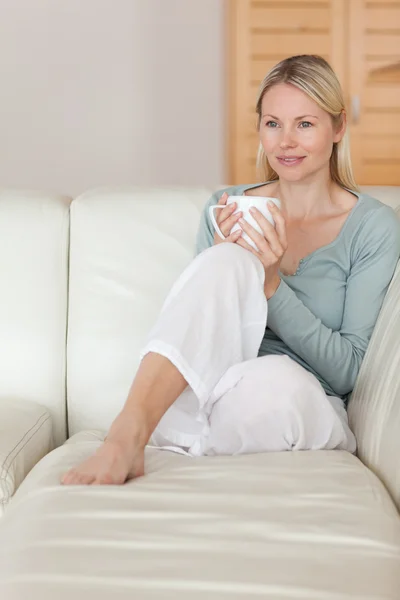Kadın kanepede rahatlatıcı bir bardak kahve ile — Stok fotoğraf