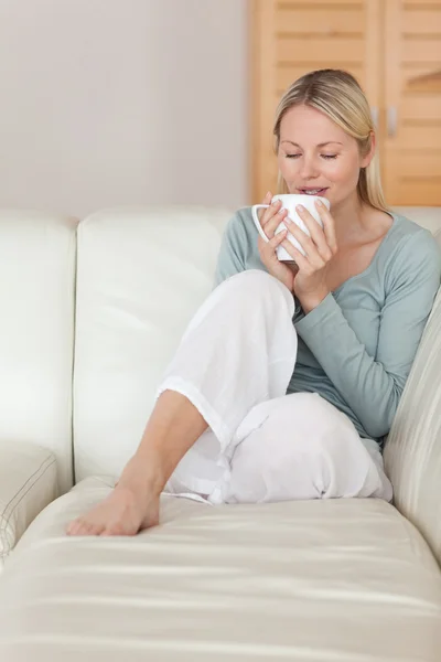 Kvinna i soffan tar en klunk kaffe — Stockfoto