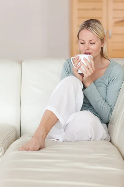 Kadın kanepede bir yudum kahve keyfi — Stok fotoğraf