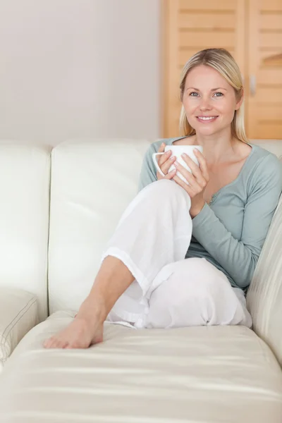Frau entspannt sich auf der Couch mit einer Tasse Kaffee — Stockfoto