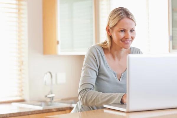 Femme souriante tapant sur son ordinateur portable — Photo