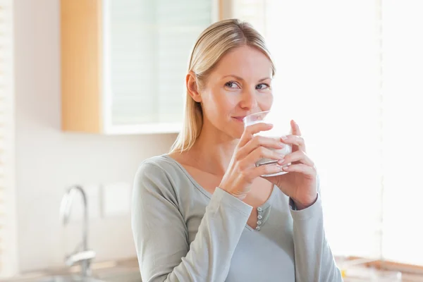 Woman standing in the kitchen drinking some water — Stock Photo, Image