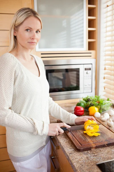 Side view of woman slicing bell pepper in the kitchen — Stock Photo, Image