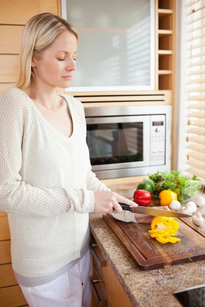 Side view of woman slicing vegetables for her salad — Stock Photo, Image