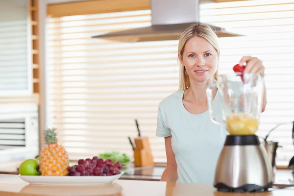Woman dropping strawberry into the blender — Stock Photo, Image