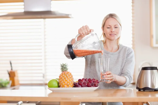Mujer vertiendo jugo hecho a sí mismo en un vaso — Foto de Stock