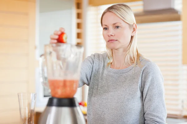 Woman putting fruits into the blender — Stock Photo, Image