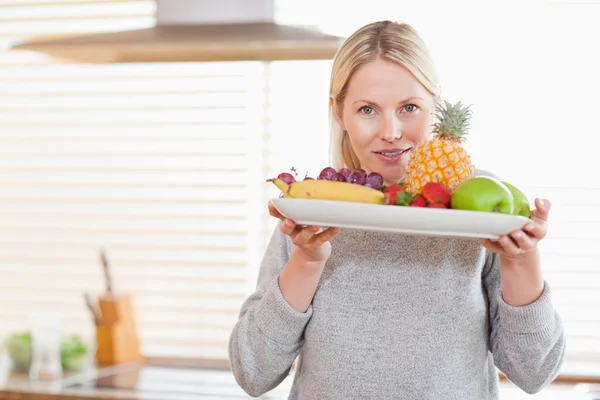 Frau hält einen Teller mit Früchten — Stockfoto