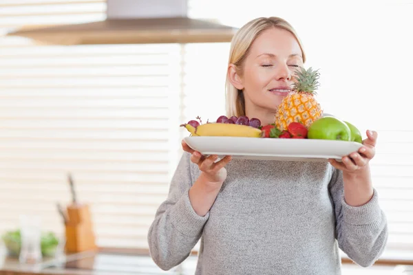 Женщина, нюхающая фруктовую тарелку — стоковое фото