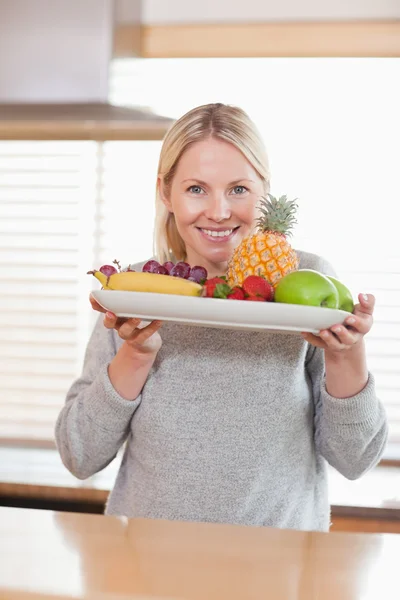 Woman presenting plate of fruits — Stock Photo, Image