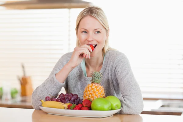 Woman in the kitchen nibbling some fruits — Stock Photo, Image