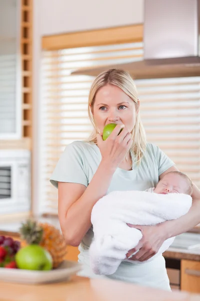 Vrouw met baby op haar arm met een appel — Stockfoto