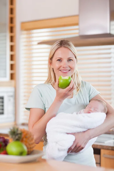 Мати з дитиною на руках має яблуко — стокове фото