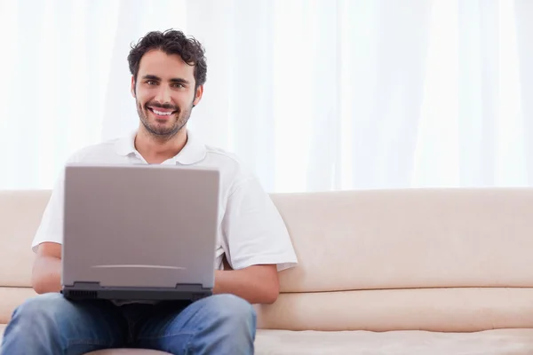 Uomo sorridente utilizzando un computer portatile — Foto Stock