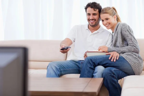 No casal de amor assistindo TV enquanto come pipocas — Fotografia de Stock