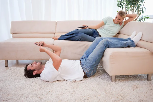 Žena, sledování televize, zatímco její přítel používá jeho cellp — Stock fotografie