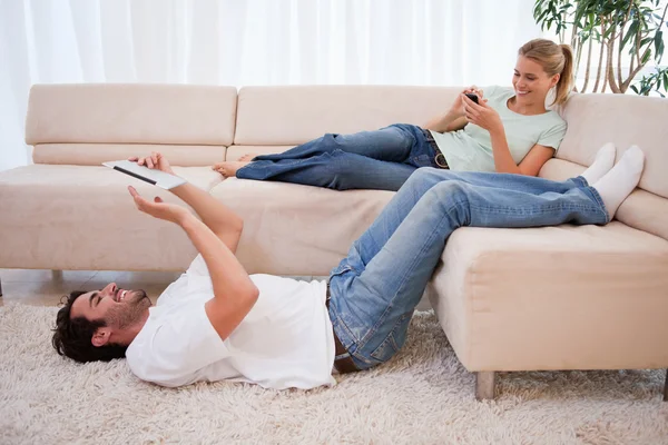 Woman using her smartphone while her boyfriend is using a tablet — Stock Photo, Image
