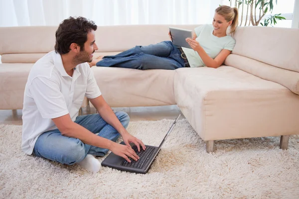 使用一台平板电脑，而她的未婚夫使用一台笔记本电脑的女人 — 图库照片