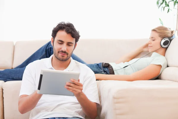 Homem usando um computador tablet enquanto sua namorada está ouvindo — Fotografia de Stock