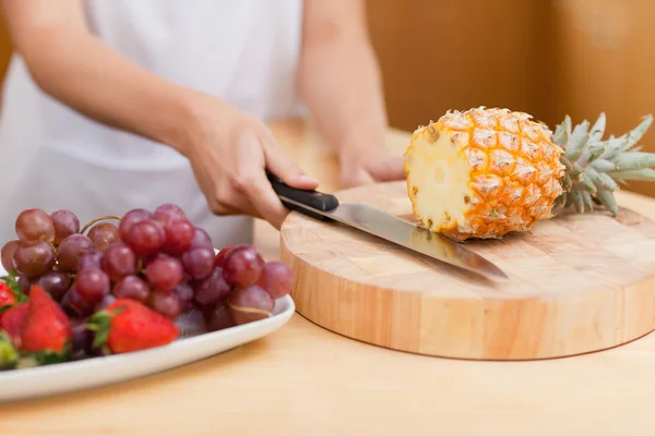 Close up van vrouwelijke handen snijden een ananas — Stockfoto