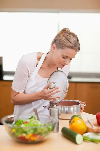 Portrait of a woman smelling in a sauce pan — Stock Photo, Image
