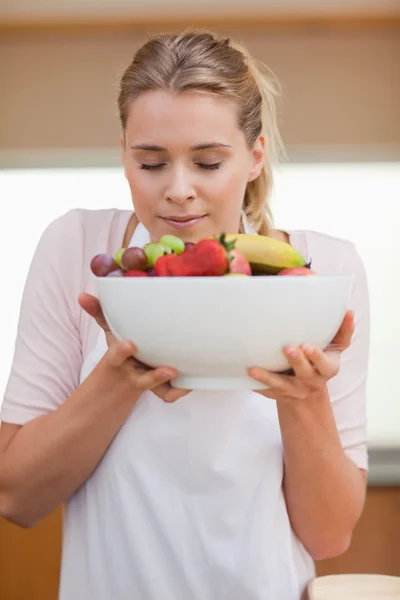 Portrait of a young woman smelling a fruit basket — Stock Photo, Image