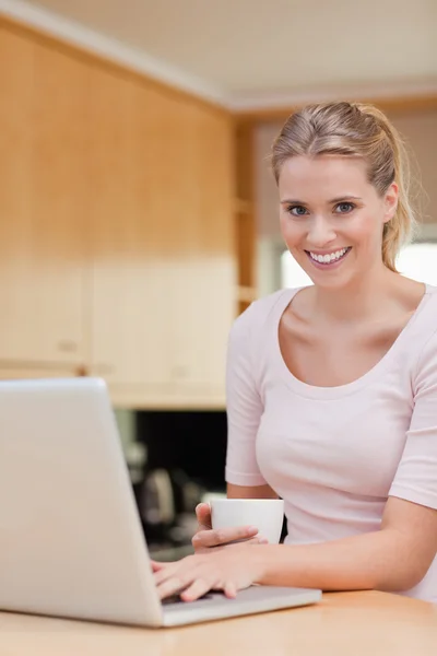 Portrait of a woman using a laptop while drinking coffee — Stock Photo, Image