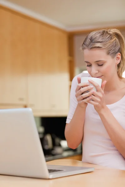Πορτρέτο μιας νεαρής γυναίκας που χρησιμοποιώντας ένα φορητό υπολογιστή ενώ το πόσιμο τσάι — Φωτογραφία Αρχείου