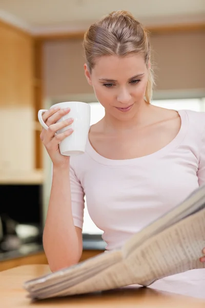 Retrato de uma jovem mulher lendo as notícias enquanto toma café — Fotografia de Stock